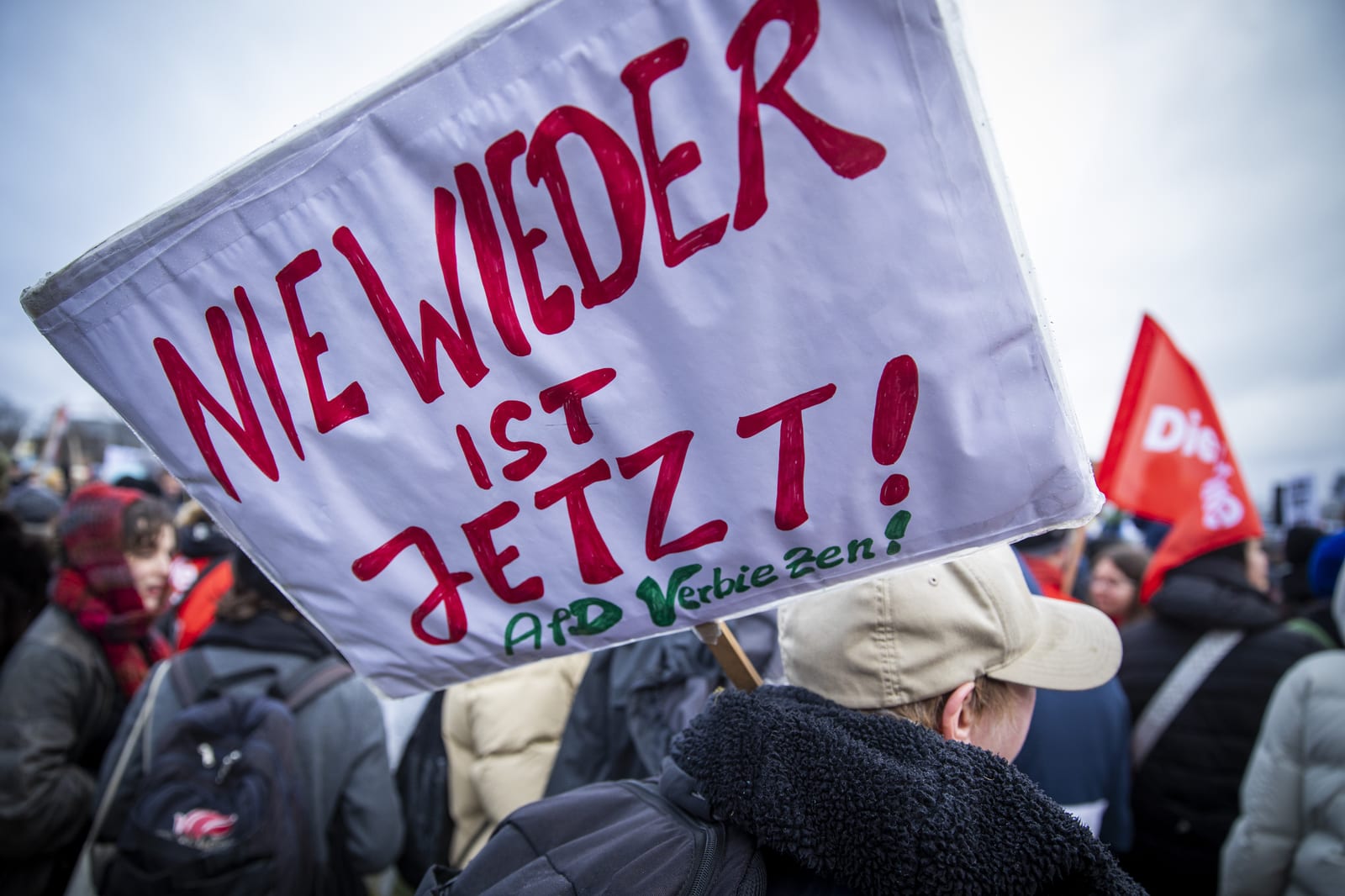 Demonstration mit Schild „Nie wieder ist jetzt!“ und DIE-LINKE-Fahne