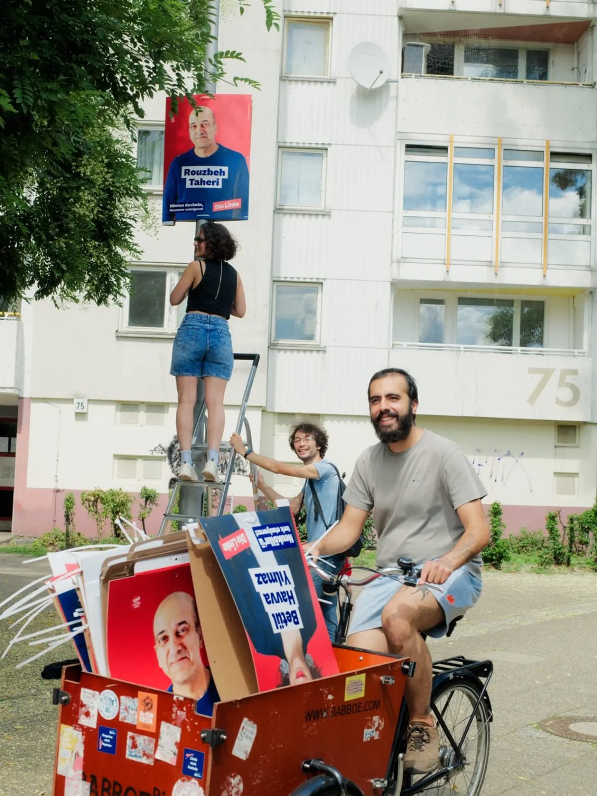 Yurtsever Özdemir mit einem Lastenrad voller Wahlplakate vor einem Hochhaus in der Gropiusstadt