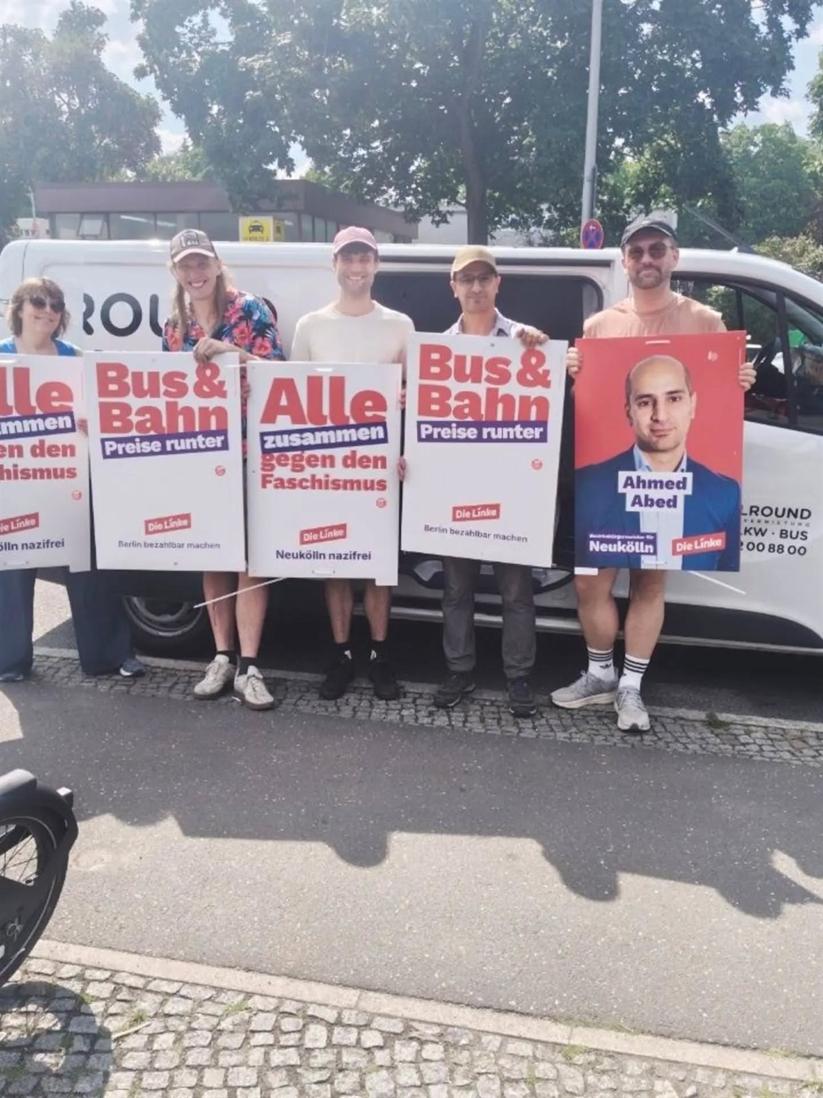 Wahlkampfteam mit DIE-LINKE-Plakaten gegen Faschismus und für günstige Bus- und Bahnpreise vor dem Kampagnen-Transporter